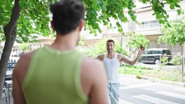 Two men couple smiling confident hugging each other at park