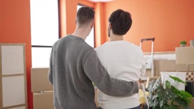 İki erkek yeni evlerinde birbirlerine sarılıyorlar.