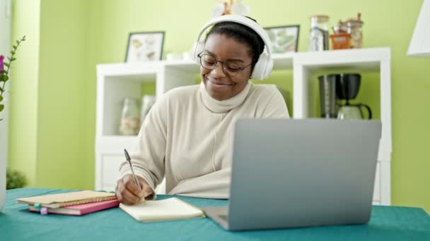 Afro Americana Usando Laptop Fones Ouvido Escrevendo Notas Estudando Sala — Vídeo de Stock