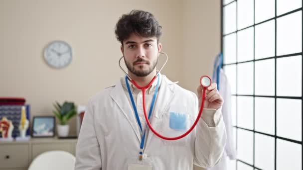 Νεαρός Ισπανός Γιατρός Χαμογελά Σίγουρος Κρατώντας Στηθοσκόπιο Στην Κλινική — Αρχείο Βίντεο