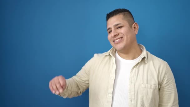 Jonge Latino Man Glimlachend Zelfverzekerd Wijzend Naar Zijkant Geïsoleerde Blauwe — Stockvideo