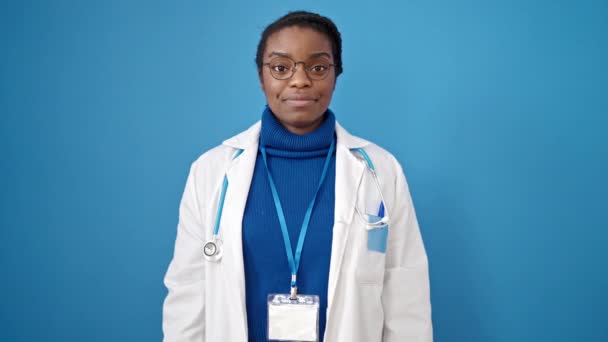 アフリカ系アメリカ人女性医師あります親指アップ上の隔離された青の背景 — ストック動画