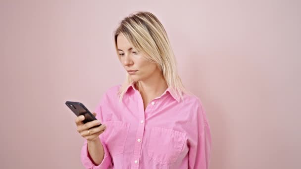 Jovem Loira Usando Smartphone Sorrindo Sobre Fundo Rosa Isolado — Vídeo de Stock