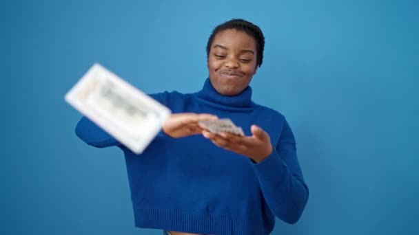 Αφροαμερικανή Γυναίκα Χαμογελά Αυτοπεποίθηση Ρίχνοντας Δολάρια Πάνω Από Απομονωμένο Μπλε — Αρχείο Βίντεο