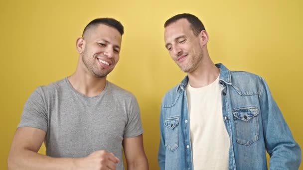 二人の男カップル笑顔自信に満ちたバンピング拳上の隔離された黄色の背景 — ストック動画