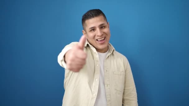 Jonge Latino Man Glimlachend Zelfverzekerd Wijzend Naar Zijkant Geïsoleerde Blauwe — Stockvideo