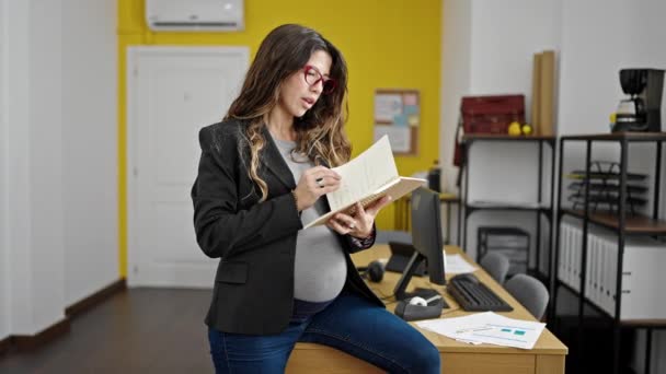 Νεαρή Έγκυος Γυναίκα Επιχειρηματίας Ανάγνωση Σημειωματάριο Στο Γραφείο — Αρχείο Βίντεο