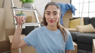 Yeni evin anahtarlarını elinde tutarak gülümseyen güzel İspanyol kadın.