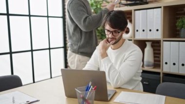 Ofiste dizüstü bilgisayarla belge okuyan iki erkek iş ortağı.
