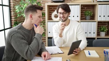 Ofiste çalışan iki erkek iş ortağı touchpad kullanıyor.