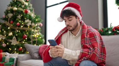 Genç İspanyol adam Noel 'i evde akıllı telefon kullanarak kutluyor.