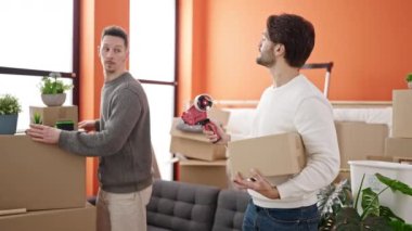 İki erkek, yeni evlerinde akıllı telefon paketleriyle fotoğraf çekiyor.
