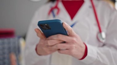 Genç İspanyol kadın doktor klinikte akıllı telefon kullanıyor.