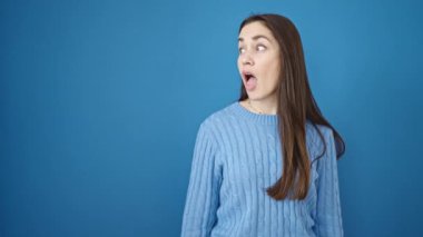 Kafkasyalı genç bir kadın gülümsüyor, mavi arka plan üzerinde yan tarafı işaret ediyor.