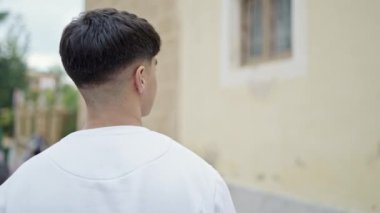 Genç İspanyol adam caddede geri geri duruyor.