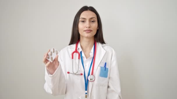 Νεαρή Όμορφη Ισπανόφωνη Γιατρός Κρατώντας Χάπια Πάνω Από Απομονωμένο Λευκό — Αρχείο Βίντεο