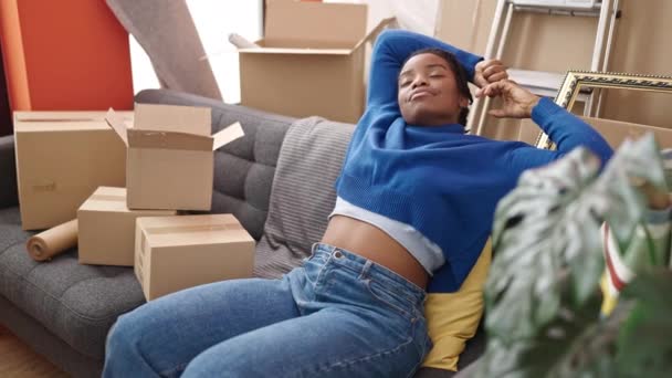 非洲裔美国女人放松了下来 双手放在头上 坐在新家里的沙发上 — 图库视频影像