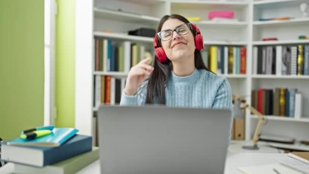 Jovem Estudante Hispânica Usando Laptop Usando Fones Ouvido Universidade Biblioteca — Vídeo de Stock