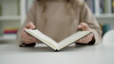 Genç, güzel İspanyol kadın öğrenci kütüphanede açılış kitabı okuyor.