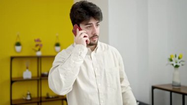 Genç İspanyol adam akıllı telefondan konuşuyor. Evde duruyor.
