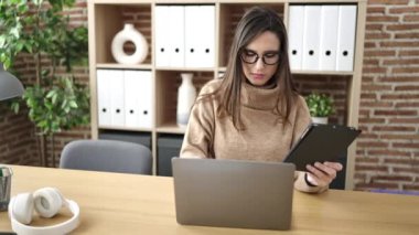 Ofiste dokunmatik ped ve dizüstü bilgisayar kullanan güzel İspanyol iş kadını.