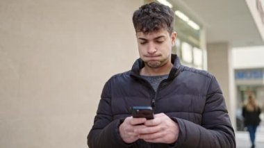 Genç İspanyol adam akıllı telefon kullanıyor. Caddeye bakıyor.