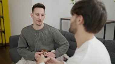 İki erkek gülümseyerek süpriz bir şekilde evde nişanlanıyorlar.