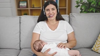 Anne ve bebek kanepede oturup evde çalışıyor.