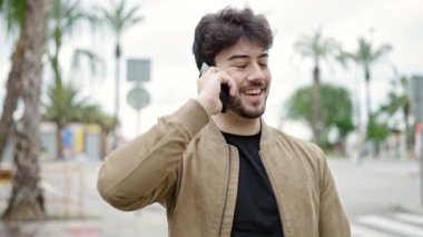 Genç İspanyol adam akıllı telefondan konuşuyor parkta gülümsüyor