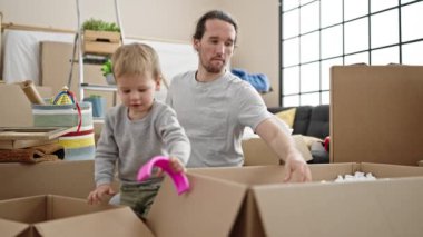 Baba ve oğul yeni evlerinde karton kutuları açıyorlar.