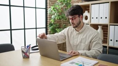 Young hispanic man business worker using laptop working at office