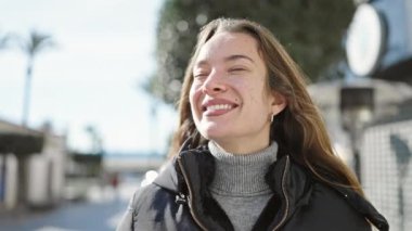 Sokakta kendine güvenen beyaz kadın gülümsüyor.