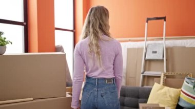 Young blonde woman smiling confident standing at new home