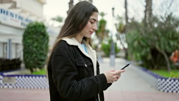 年轻美丽的惊慌失措的女人在公园里用带有严肃表情的智能手机 — 图库视频影像