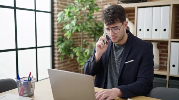 Jovem Hispânico Homem Empresário Falando Telefone Usando Laptop Escritório — Vídeo de Stock