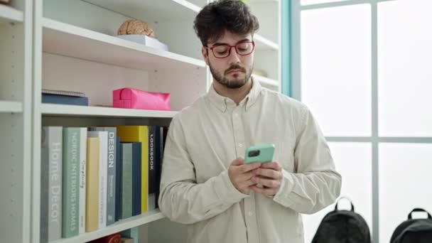 Joven Estudiante Hispano Sonriendo Confiado Usando Smartphone Universidad Biblioteca — Vídeos de Stock