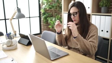 Ofiste çalışan güzel İspanyol iş kadını dizüstü bilgisayar kullanıyor.