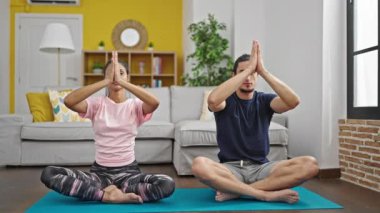Erkek ve kadın çift gülümseyerek evde yoga egzersizi yapıyorlar.