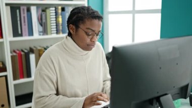 African american woman student using computer stressed at library university