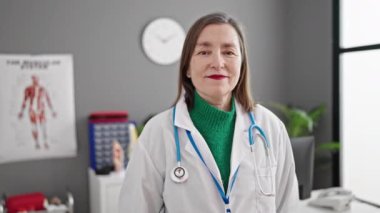 Gri saçlı doktorla klinikte parmak işi yapan olgun İspanyol kadın.