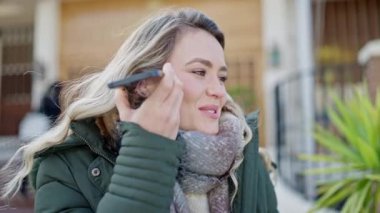 Young blonde woman listening to voice message at street