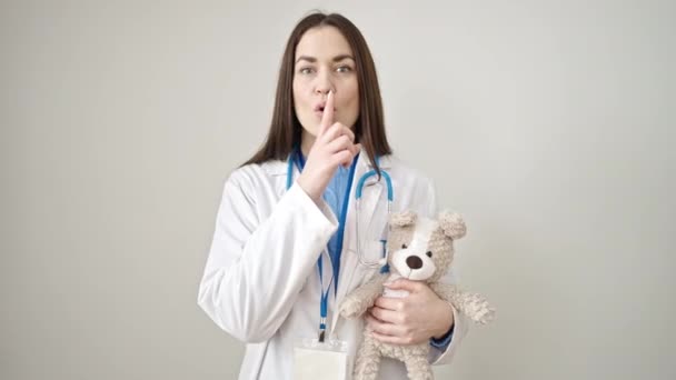 年轻的高加索女医生要求安静地把泰迪熊抱在孤立的白色背景上 — 图库视频影像