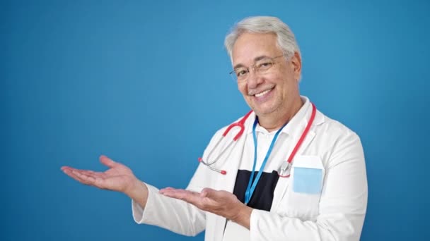 中年男子 白发医生面带微笑 自信地表现出孤立的蓝色背景 — 图库视频影像