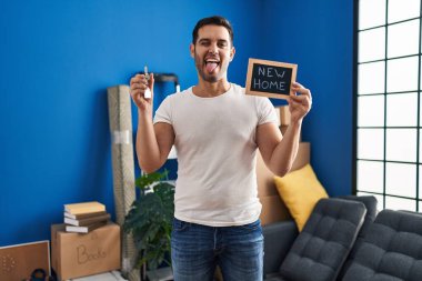 Sakallı genç İspanyol bir adam elinde yeni evinin anahtarlarıyla mutlu bir ifadeyle dilini dışarı çıkarıyor.. 