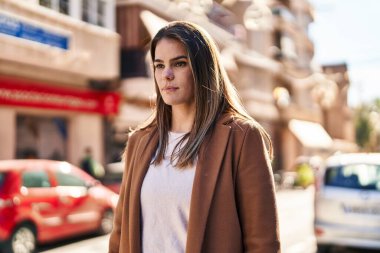 Young beautiful hispanic woman looking to the side with serious expression at street