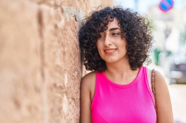 Orta Doğulu genç bir kadın oyun odasında kendine güvenen bir şekilde yan tarafa bakıyor.