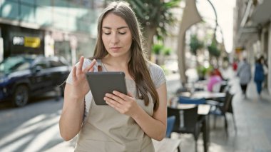 Genç ve güzel İspanyol bayan garson kafe terasında dokunmatik ped kullanıyor.
