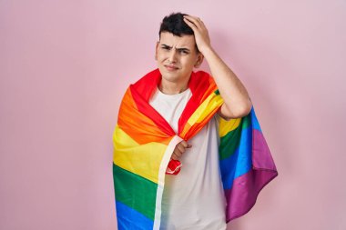 İkili olmayan kişi elinde gökkuşağı lgbtq bayrağı tutarken gergin ve hayal kırıklığına uğramış, şaşırmış ve kızgın bir yüz. 