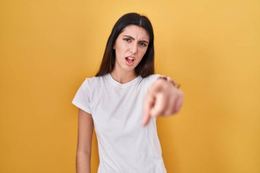 Sarı arka planda duran genç ve güzel bir kadın kameraya kızgın ve sinirli olduğunu gösteriyor. 