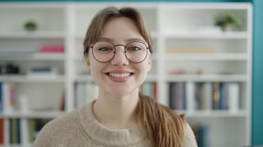 Young blonde woman student smiling confident standing at library university